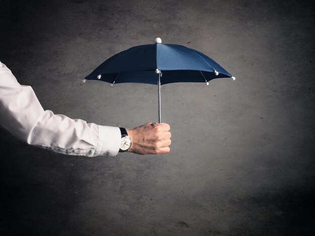 Abgeschnittene Hand eines Mannes, der einen Regenschirm an der Wand hält