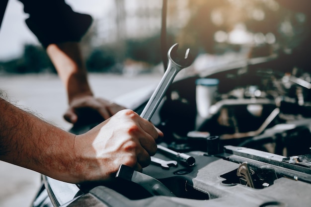 Foto abgeschnittene hand eines mannes, der in einer garage an einem auto arbeitet