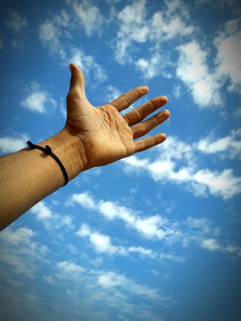 Foto abgeschnittene hand eines mannes, die den blauen himmel erreicht
