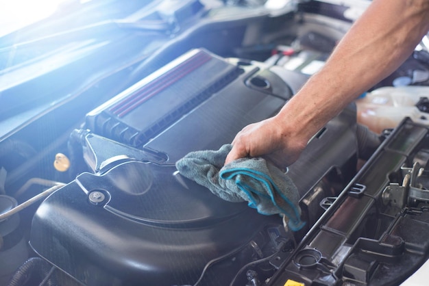Abgeschnittene Hand eines Mechanikers, der den Motor in einer Garage repariert