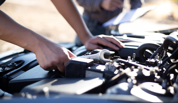 Foto abgeschnittene hand eines mechanikers, der einen automotor in einer werkstatt repariert