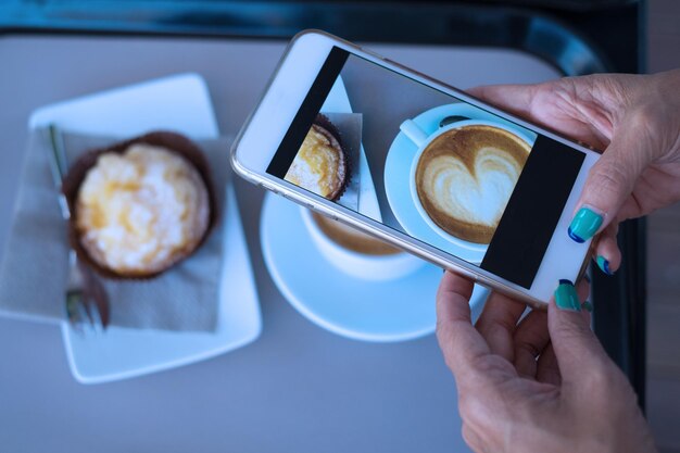 Foto abgeschnittene hand fotografiert eine kaffeetasse mit einem handy