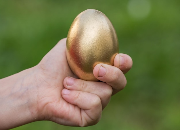 Abgeschnittene Hand hält ein goldenes Osterei