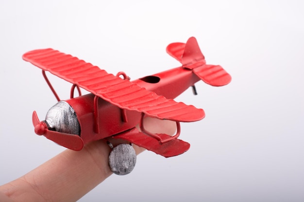 Foto abgeschnittene hand hält ein rotes modellflugzeug vor weißem hintergrund