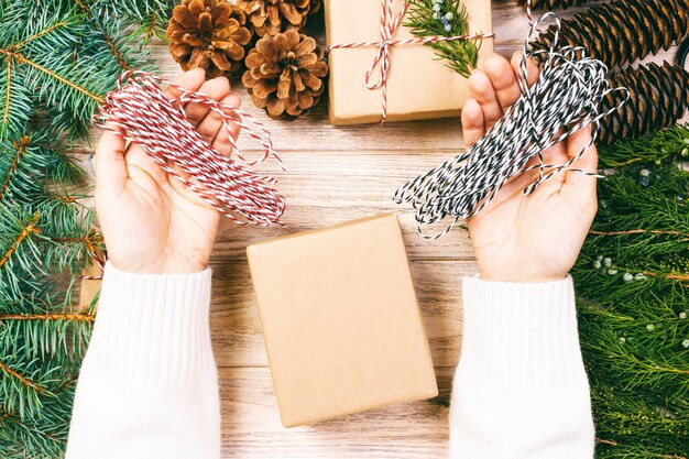 Foto abgeschnittene hand hält ein weihnachtsgeschenk auf dem tisch