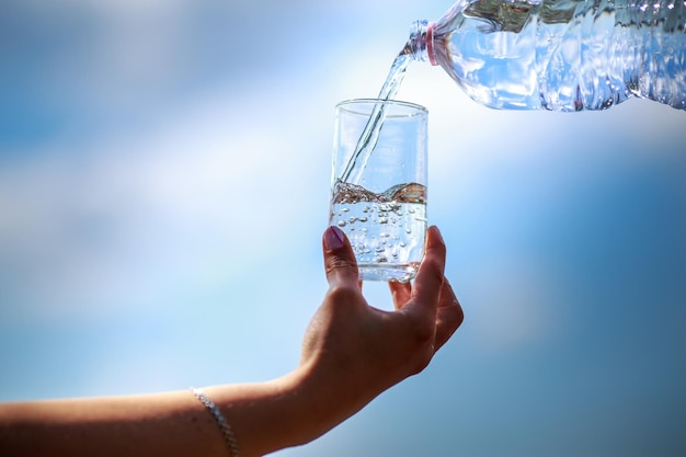 Abgeschnittene Hand hält Glas gegen den Himmel