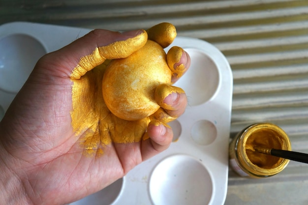 Abgeschnittene Hand mit golden gemaltem Ostereiern