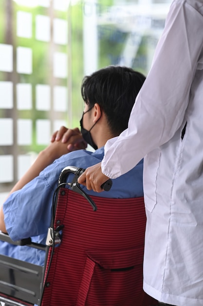 Abgeschnittene Schusskrankenschwester, die ihren Patienten im Rollstuhl schiebt.