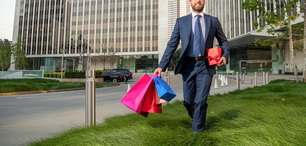 Abgeschnittener Geschäftsmann im Anzug hält Pakete und Geschenkboxen außerhalb des Bürokopierraums herrentag