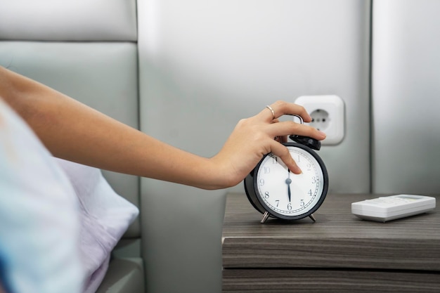 Foto abgeschnittener hand-schläfer-wecker im schlafzimmer zu hause