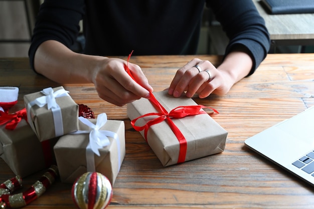 Abgeschnittener Schuss junger Mann, der Weihnachtsgeschenke verziert.