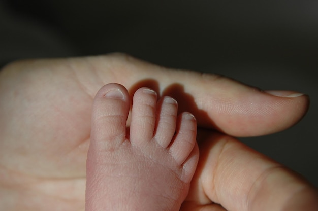 Abgeschnittenes Bein auf dem Sohn berührt den Vater Hand gegen schwarzen Hintergrund