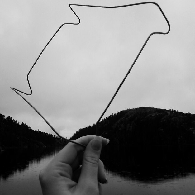 Foto abgeschnittenes bild einer frau mit einer metallhand am see gegen berge und himmel