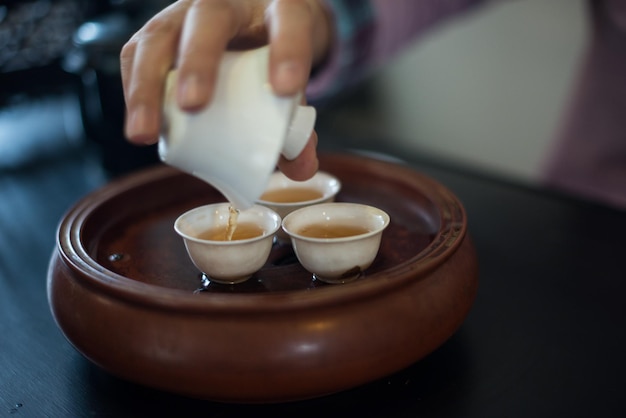 Abgeschnittenes Bild einer Hand, die chinesischen Tee in eine Tasse gießt