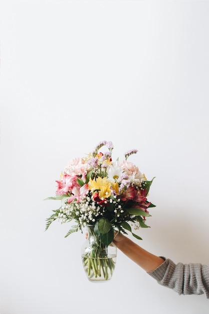 Abgeschnittenes Bild einer Hand, die eine Blumenvase an der Wand hält
