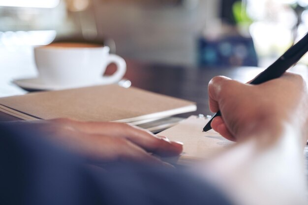 Foto abgeschnittenes bild einer hand, die eine kaffeetasse auf dem tisch hält