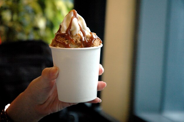 Foto abgeschnittenes bild einer hand, die einen kaffee-eisbecher hält