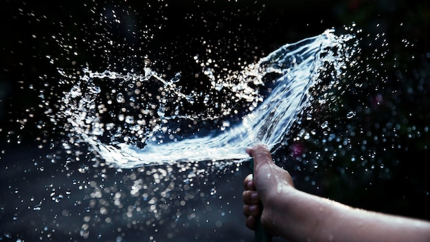 Abgeschnittenes Bild einer Hand, die im Freien Wasser sprüht