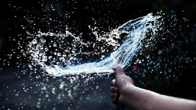 Foto abgeschnittenes bild einer hand, die im freien wasser sprüht