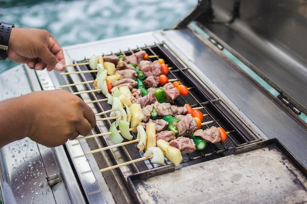 Abgeschnittenes Bild einer Person, die Essen auf einem Grill zubereitet