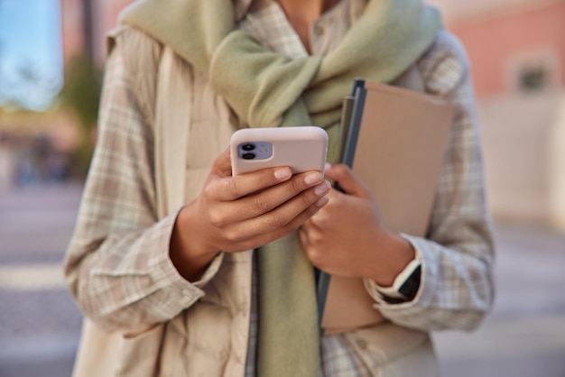 Abgeschnittenes Bild einer unbekannten Frau in Freizeitkleidung hält Handy durchsucht Webpublikation