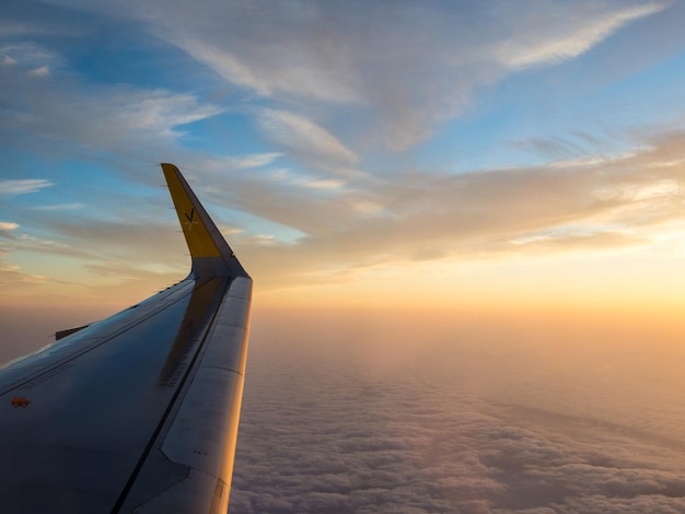 Abgeschnittenes Bild eines Flugzeugflügels gegen den Himmel bei Sonnenuntergang