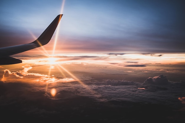 Abgeschnittenes Bild eines Flugzeugs, das während des Sonnenuntergangs gegen den Himmel fliegt