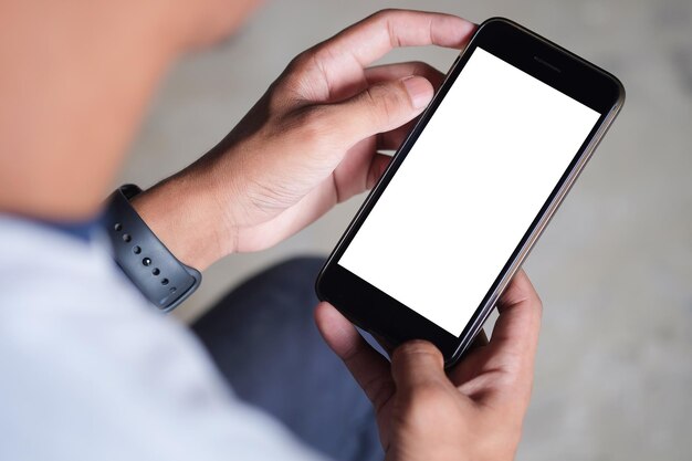 Foto abgeschnittenes bild eines jungen mannes, der ein smartphone mit weißem bildschirm benutzt, während er in einem modernen büro sitzt