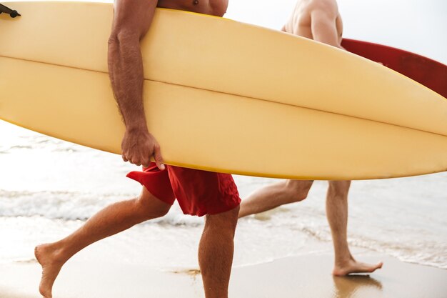 Abgeschnittenes Bild eines jungen zwei Männer Surfer Freunde mit Surfen an einem Strand draußen.