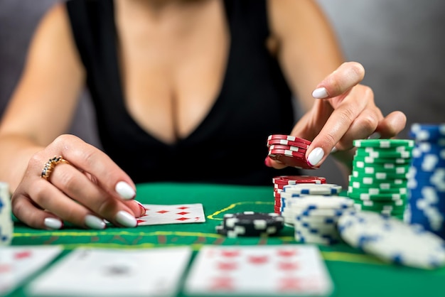 Abgeschnittenes Bild eines Mädchens im Abendkleid, das Poker spielt und Chips am Casino-Tisch nimmt