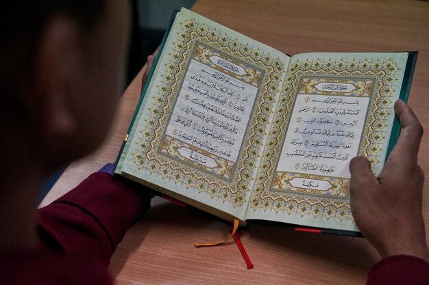 Foto abgeschnittenes bild eines mannes, der den koran auf dem tisch liest