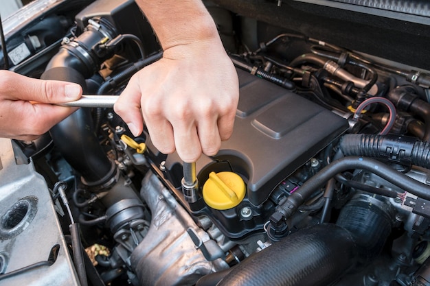 Abgeschnittenes Bild eines Mannes, der den Motor eines Autos repariert