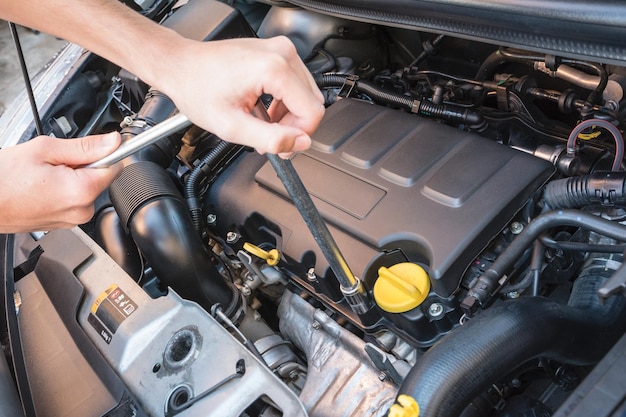 Abgeschnittenes Bild eines Mannes, der den Motor eines Autos repariert
