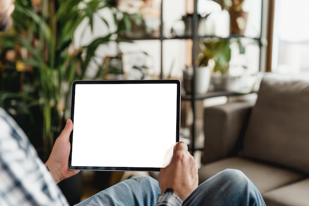 Abgeschnittenes Bild eines Mannes, der ein digitales Tablet mit leerem Bildschirm zu Hause hält