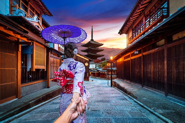 Foto abgeschnittenes bild eines mannes, der hand in hand mit seiner freundin in kimono in der stadt hält