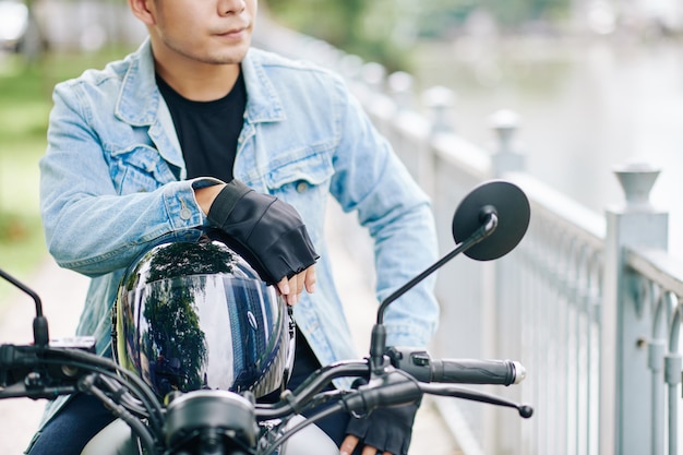 Abgeschnittenes Bild eines selbstbewussten ernsthaften Mannes mit Helm, der auf dem Motorrad sitzt