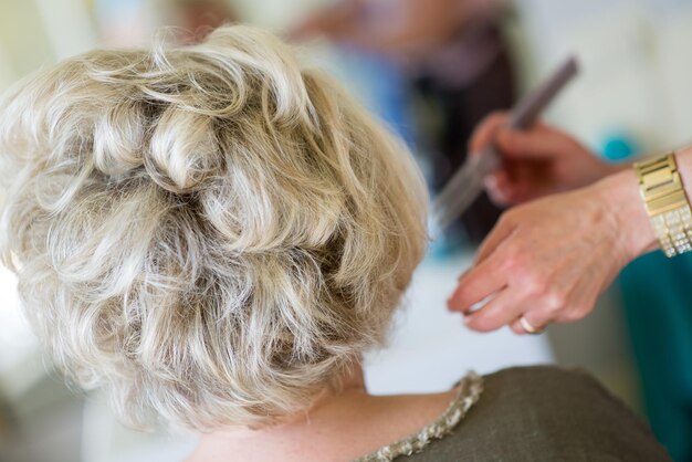 Abgeschnittenes Bild von einem Friseur, der die Haare eines Kunden im Salon stylt