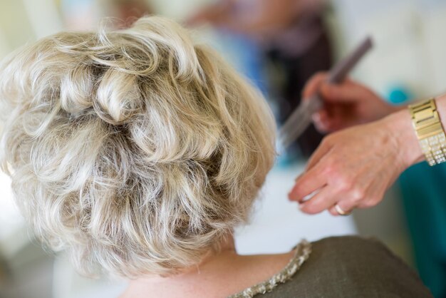 Foto abgeschnittenes bild von einem friseur, der die haare eines kunden im salon stylt