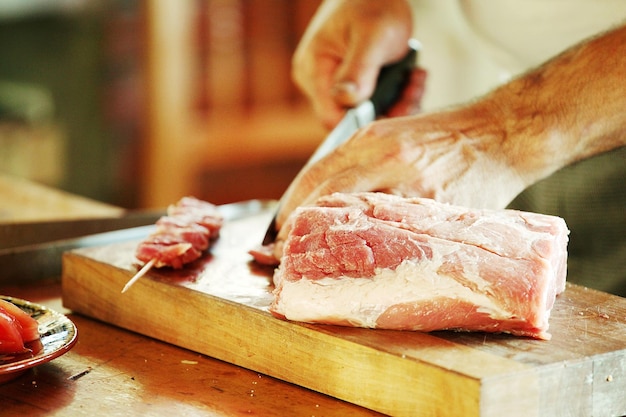 Abgeschnittenes Bild von einem Koch, der Fleisch schneidet