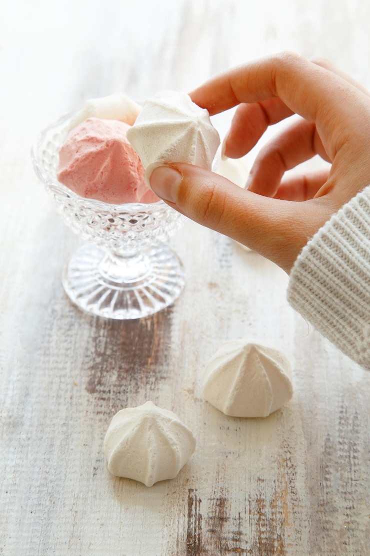 Foto abgeschnittenes bild von frauenhänden, die meringue über dem tisch halten