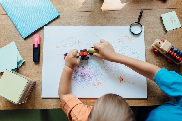 Foto abgeschnittenes bild von geschwistern, die an einem tisch mit spielzeugwagen spielen