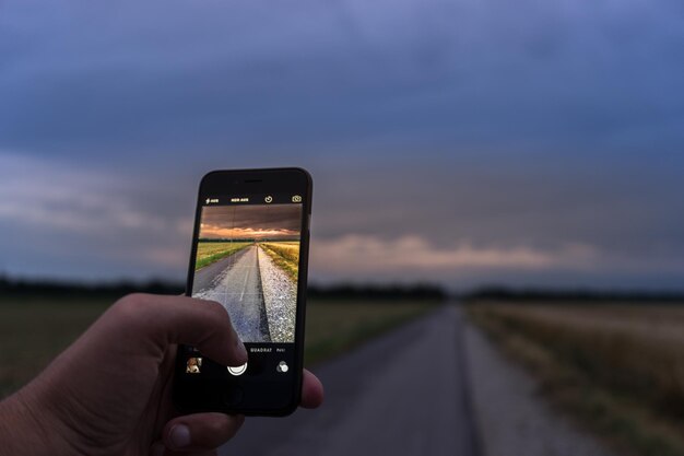 Foto abgeschnittenes bild von händen, die eine landstraße fotografieren