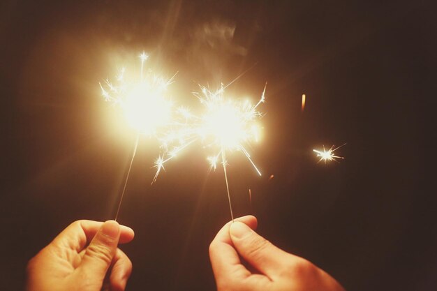 Abgeschnittenes Bild von Menschen, die nachts ein Funkeln in der Hand halten