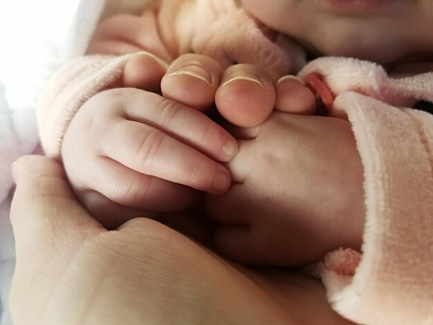 Foto abgeschnittenes bild von mutter und baby, die sich die hände halten