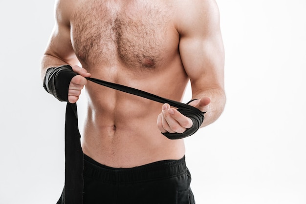 Abgeschnittenes Foto eines gutaussehenden Boxers, der über weißer Wand steht.