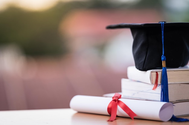 Abgeschnittenes Foto eines Hochschulabschlusshutts und eines Diplomzeugnisses auf dem Tisch