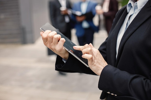 Abgeschnittenes Foto von Händen einer Geschäftsfrau, die steht und ein Tablet verwendet