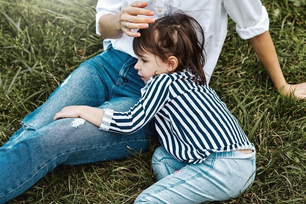 Abgeschnittenes horizontales Bild einer schönen Frau, die mit ihrem niedlichen kleinen Mädchen auf dem grünen Gras im Freien spielt Glückliches Kind und Mutter verbringen Zeit zusammen im Park Muttertagskonzept