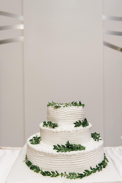 Abgestufter weißer Kuchen der Luxushochzeit verziert mit Blumenfoto nachts auf dem Hintergrund von Lichtern