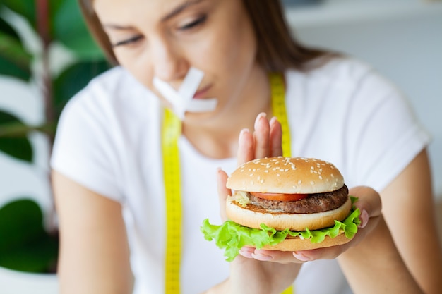 Abnehmen Konzept, junge Frau mit versiegeltem Mund Junk Food aufgeben.